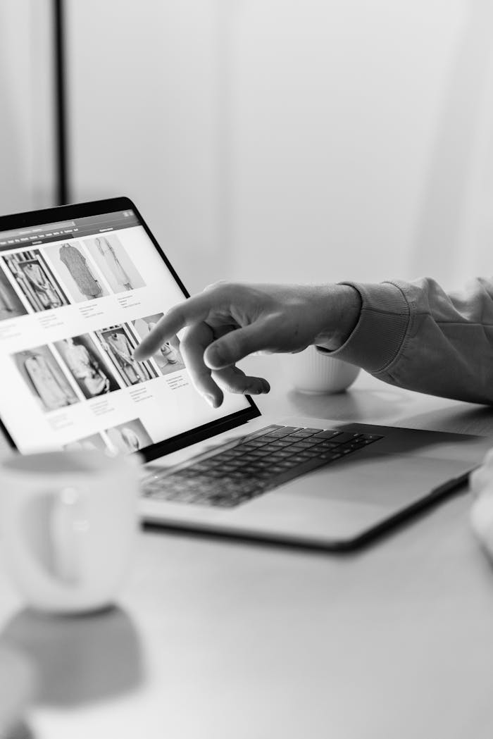 Services-01 Black and white photo of a person shopping online on a laptop, highlighting e-commerce technology.
